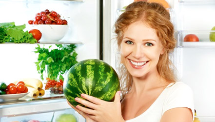 Mädchen hält Wassermelone im Kühlschrank