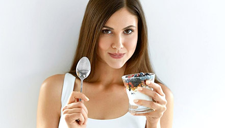 Krásná dívka jíst ostružiny s jogurtem