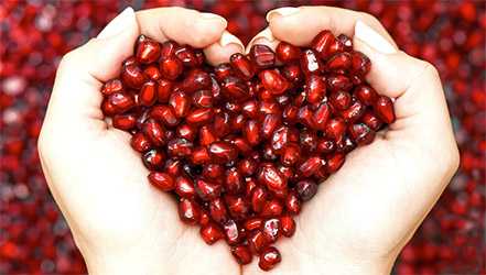 Semințe de rodie în mâini în formă de inimă
